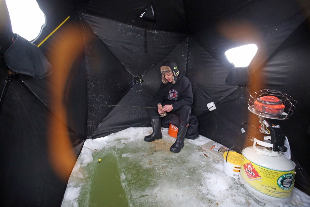 Lens flares from the two open tent windows encircle Brandon resident Tyle Baker, who decided to spend his Tuesday on the Assiniboine River for a little ice fishing. On Monday, he says he pulled four Walleye out of the river at his spot near the Riverbank Discovery Centre trail. But as of Tuesday noon, he had yet to catch anything. (Matt Goerzen/The Brandon Sun)