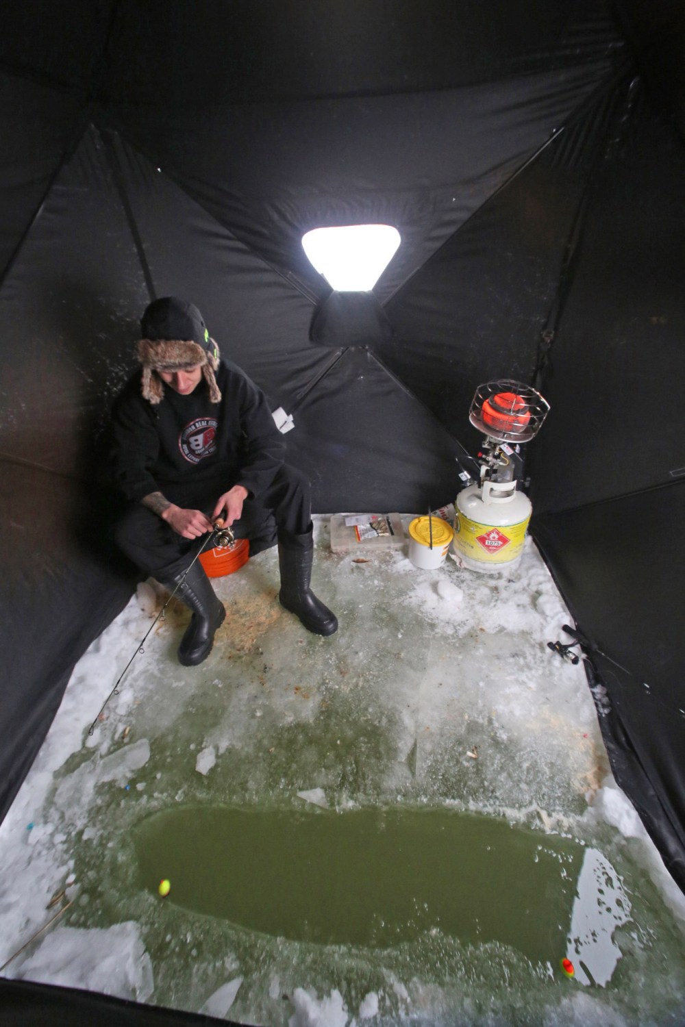 Tyler Baker of Brandon takes a little time on Tuesday afternoon to get in some ice fishing on the Assiniboine River just down the trail from the Riverbank Discovery Centre. He's seen here in his two-man ice fishing tent. (Matt Goerzen/The Brandon Sun)