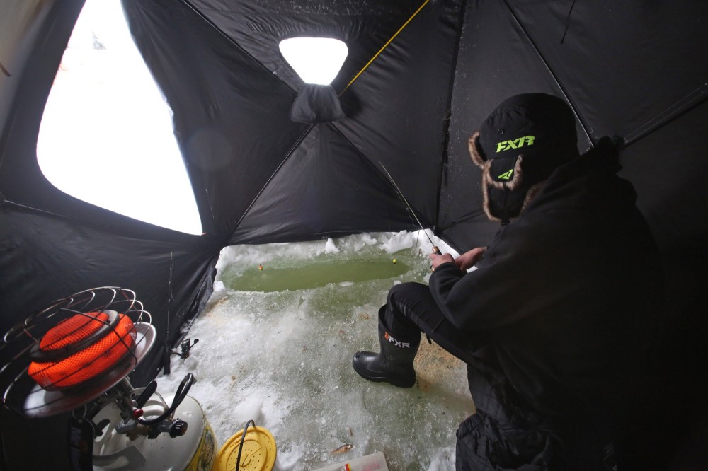 Tyler Baker of Brandon takes a little time on Tuesday afternoon to get in some ice fishing on the Assiniboine River just down the trail from the Riverbank Discovery Centre. He's seen here in his two-man ice fishing tent. (Matt Goerzen/The Brandon Sun)