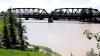 Crews work to stabilize a Canadian Pacific freight train as is sits derailed on a failing bridge over the flooded Bow River in Calgary on Thursday, June 27, 2013. THE CANADIAN PRESS/Jeff McIntosh