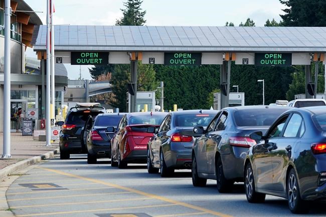 A line of vehicles wait to enter Canada at the Peace Arch border crossing Monday, Aug. 9, 2021, in Blaine, Wash. Border-city mayors, tourism industry leaders and an opposition MP say it’s time to bid a less-than-fond farewell to the ArriveCan app. (AP Photo/Elaine Thompson)