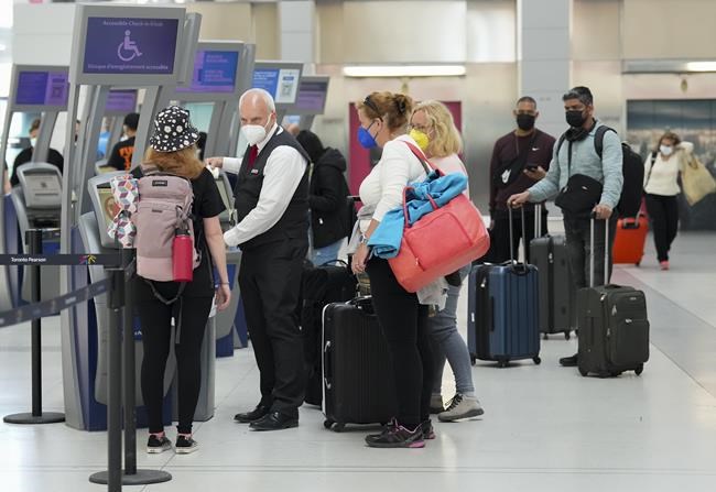 People wait in line to check in at Pearson International Airport in Toronto on Thursday, May 12, 2022. Canada's transport regulator is beefing up passenger protection rules, placing more stringent rules around reimbursement by airlines. THE CANADIAN PRESS/Nathan Denette