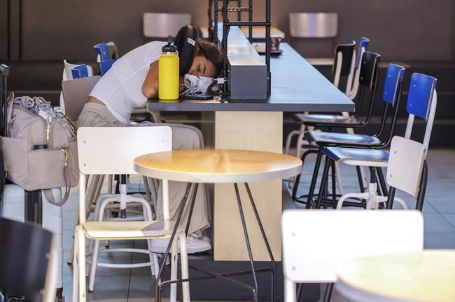 FILE - A woman sleeps on a charging station table in the departures hall at Brussels international airport during a general strike in Brussels, Monday, June 20, 2022. (AP Photo/Olivier Matthys, File)