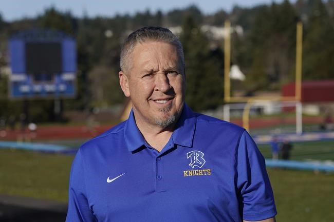FILE - Joe Kennedy, a former assistant football coach at Bremerton High School in Bremerton, Wash., poses for a photo March 9, 2022, at the school's football field. The Supreme Court has sided with a football coach from Washington state who sought to kneel and pray on the field after games. The court ruled 6-3 along ideological lines for the coach. The justices said Monday the coach's prayer was protected by the First Amendment. (AP Photo/Ted S. Warren, File)