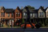 A person walks by a row of houses in Toronto on Tuesday July 12, 2022. Multigenerations living under one roof is becoming increasingly common, Statistics Canada's latest tranche of census data revealed Wednesday.THE CANADIAN PRESS/Cole Burston