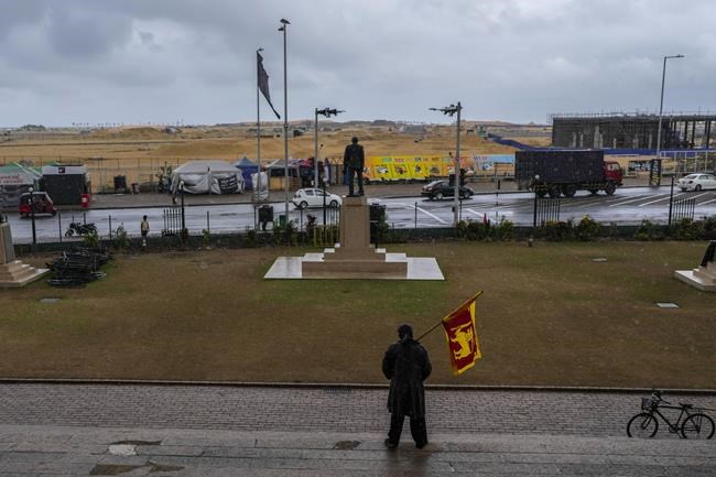 A protester stands holding Sri Lankan flag in the compound of presidential secretariat the day after Ranil Wickremesinghe was elected president in Colombo, Sri Lanka, Thursday, July 21, 2022. Sri Lanka's prime minister was elected president Wednesday by lawmakers who opted for a seasoned, veteran leader to lead the country out of economic collapse, despite widespread public opposition.(AP Photo/Rafiq Maqbool)