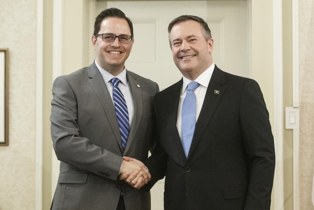 Alberta Premier Jason Kenney shakes hands with Demetrios Nicolaides, minister of advanced education, after being sworn into office, in Edmonton on April 30, 2019. The Alberta government has upped the ante in its fight with Athabasca University, directing the online-oriented school to get busy making sure more staff work in the small northern town or risk losing millions of dollars in funding. THE CANADIAN PRESS/Jason Franson