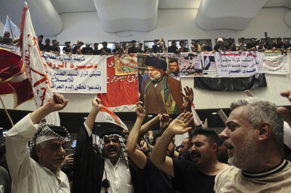 Followers of Shiite cleric Muqtada al-Sadr hold posters with his photo during a sit-in, inside the parliament in Baghdad, Iraq, Tuesday, Aug. 2, 2022. (AP Photo/Adil al-Khazali)