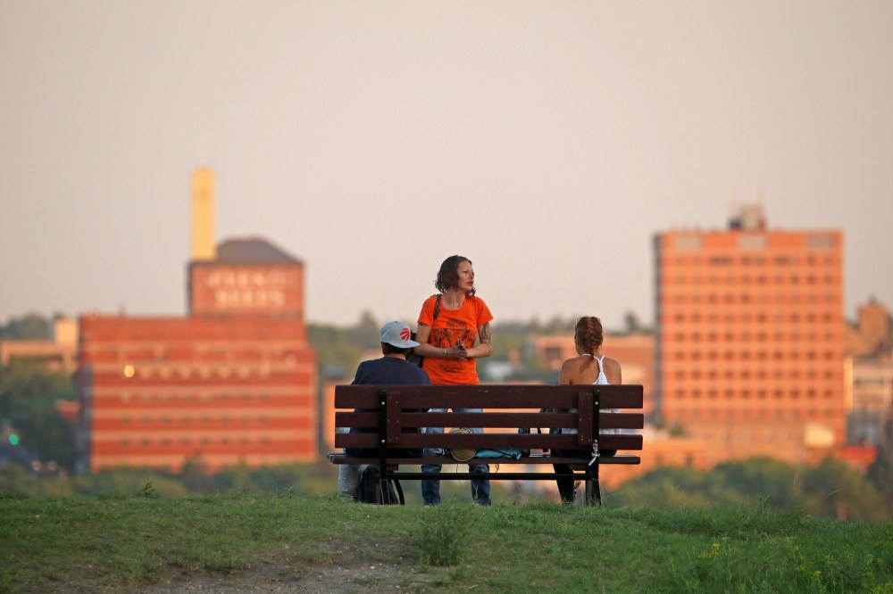 A group look out over the downtown Brandon skyline from Hanbury Hill on a hot Tuesday evening in this file image. (Tim Smith/The Brandon Sun)