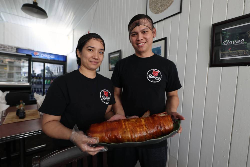 Sunshine (left) and Ryan Bahena of Brandon's first Filipino restaurant, Robyns Lechon, show off roast pork belly made in-house. (Colin Slark/The Brandon Sun)