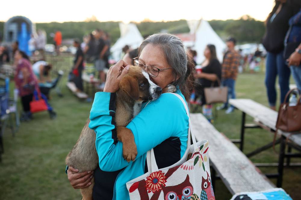 Sandi Leithwoot, of Brandon, holds a puppy while watching the Grand Entry at the Sioux Valley Dakota Nation Powwow Friday evening. (Tim Smith/The Brandon Sun)