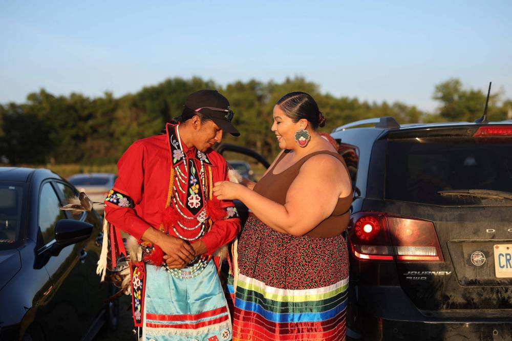 Fawn Meshake helps her husband Preston Kashkish attach plumes to his regalia at the Sioux Valley Dakota Nation Powwow Friday evening. (Tim Smith/The Brandon Sun)