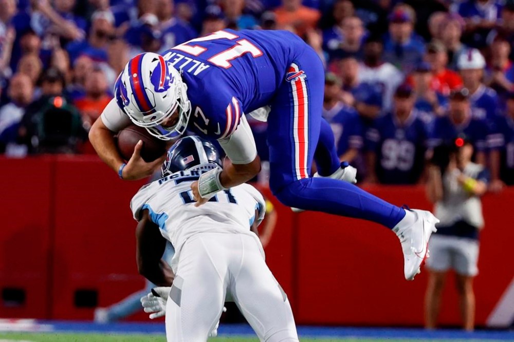 Buffalo Bills quarterback Josh Allen (17) leaps over Tennessee Titans' Roger McCreary (21) during the first half of an NFL football game Monday, Sept. 19, 2022, in Orchard Park, N.Y. THE CANADIAN PRESS/AP/Jeffrey T. Barnes