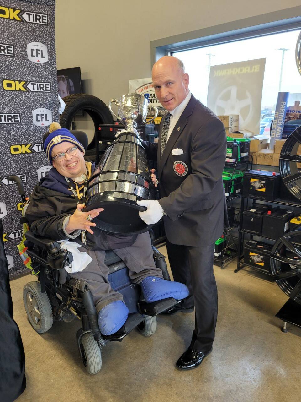 Lifelong football fan Rodney McKnight (left) got a chance to hold the Grey Cup and meet the Keeper of the Cup, Jeff McWhinney (right), at the OK Tire location at Zorzo's Auto Sales in Brandon on Saturday. (Miranda Leybourne/Brandon Sun)