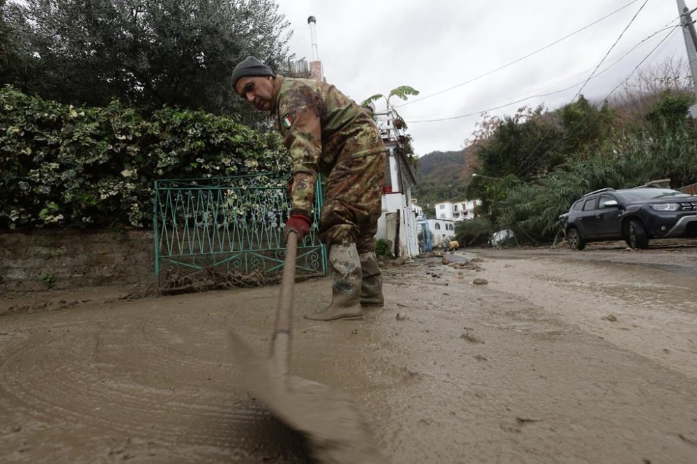 A rescuer removes mud from a street after heavy rainfall triggered landslides that collapsed buildings and left as many as 12 people missing, in Casamicciola, on the southern Italian island of Ischia, Italy, Saturday, Nov. 26, 2022. Firefighters are working on rescue efforts as reinforcements are being sent from nearby Naples, but are encountering difficulties in reaching the island either by motorboat or helicopter due to the weather. (Alessandro Garofalo/LaPresse via AP)