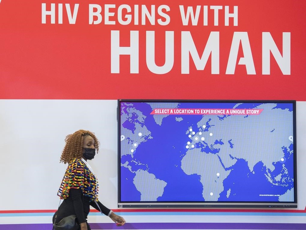 A woman walks by a sign during the AIDS 2022 conference in Montreal, Sunday, July 31, 2022. HIV activists are marking World AIDS Day by urging Ottawa to help stop a global backslide in progress on stemming infections and stigma. THE CANADIAN PRESS/Graham Hughes