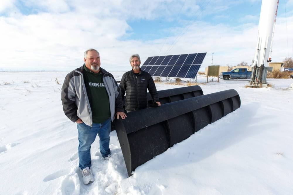 Yves Maynard (left) and Don Walker (right), co-owners of Kynetic Energy Solutions, pose for a photo with a combined solar and wind turbine package they say requires little wind to generate power. (Winnipeg Free Press)