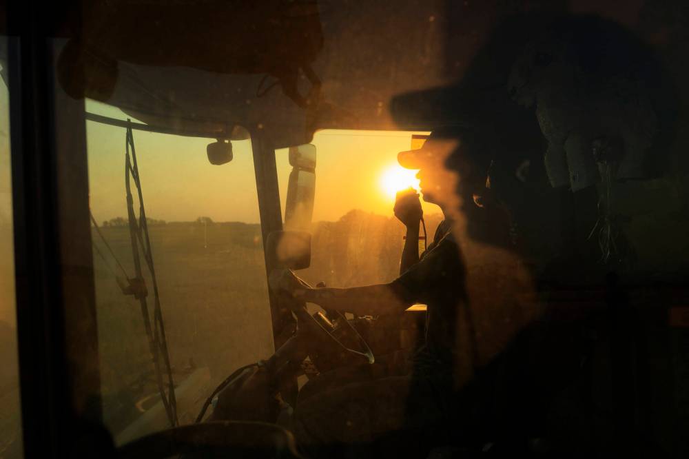 Cassandra Lepp talks over the radio while combining barley north of Rivers along with her sister Stefanie in a nearby combine.
