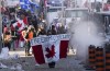 Protesters participating in a cross-country truck convoy protesting measures taken by authorities to curb the spread of COVID-19 and vaccine mandates walk near Parliament Hill in Ottawa on Saturday, Jan. 29, 2022. The 