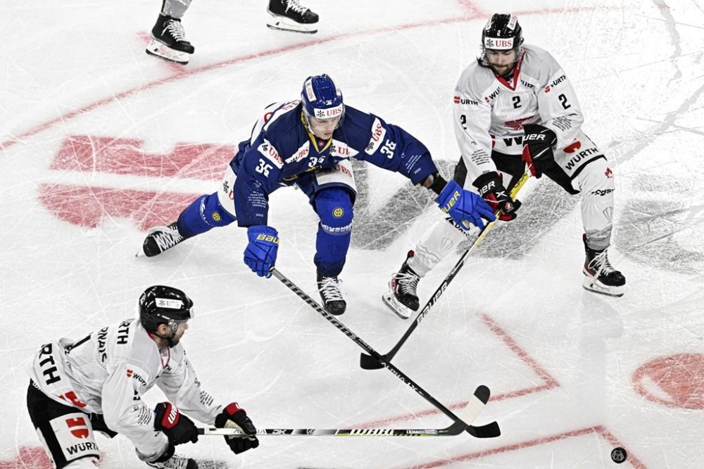 Davos' Simon Knak, center, and Canada's Thomas Gregoire, right, during the game between Switzerland's HC Davos and Team Canada at the 94th Spengler Cup ice hockey tournament in Davos, Switzerland, Tuesday, Dec. 27, 2022. THE CANADIAN PRESS/Gian Ehrenzeller/Keystone via AP