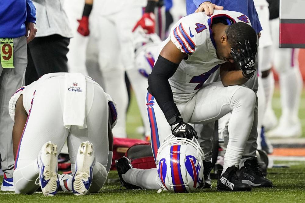 Buffalo Bills players and staff pray for Bills safety Damar Hamlin during the first half of an NFL game against the Cincinnati Bengals on Jan. 2. Hamlin collapsed on the field after suffering cardiac arrest. (The Associated Press)