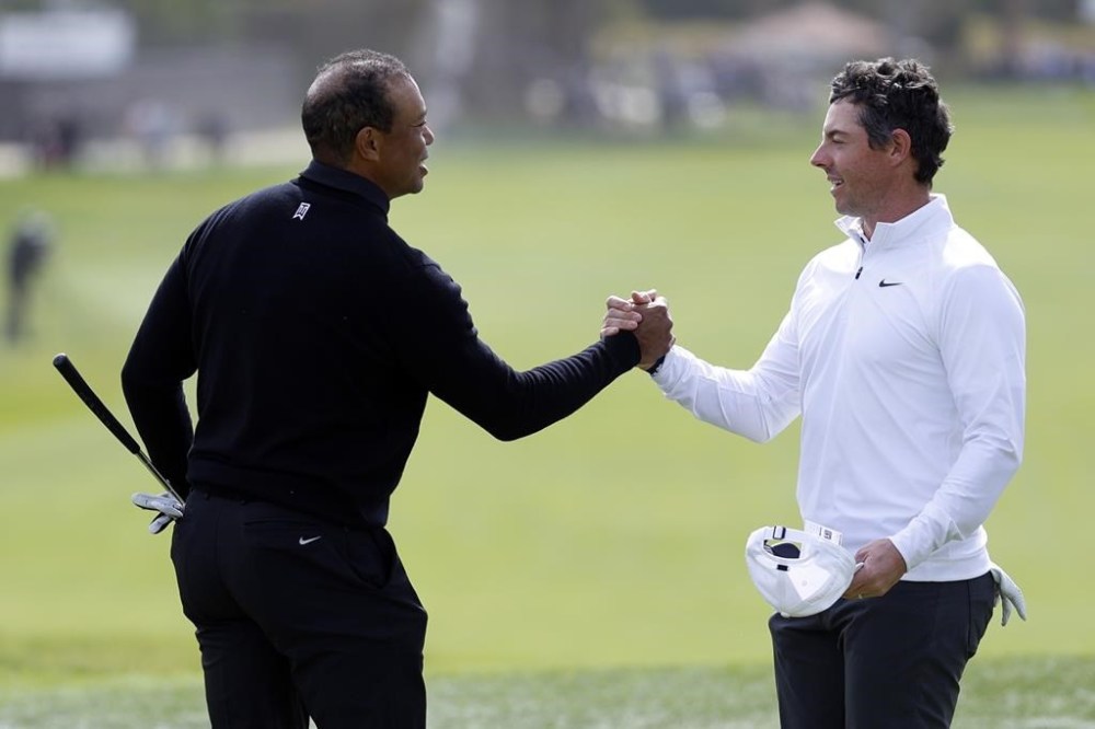 Tiger Woods, left, shakes hands with Rory McIlroy on the ninth green after they both finished the second round of the Genesis Invitational golf tournament at Riviera Country Club, Friday, Feb. 17, 2023, in the Pacific Palisades area of Los Angeles. (AP Photo/Ryan Kang)