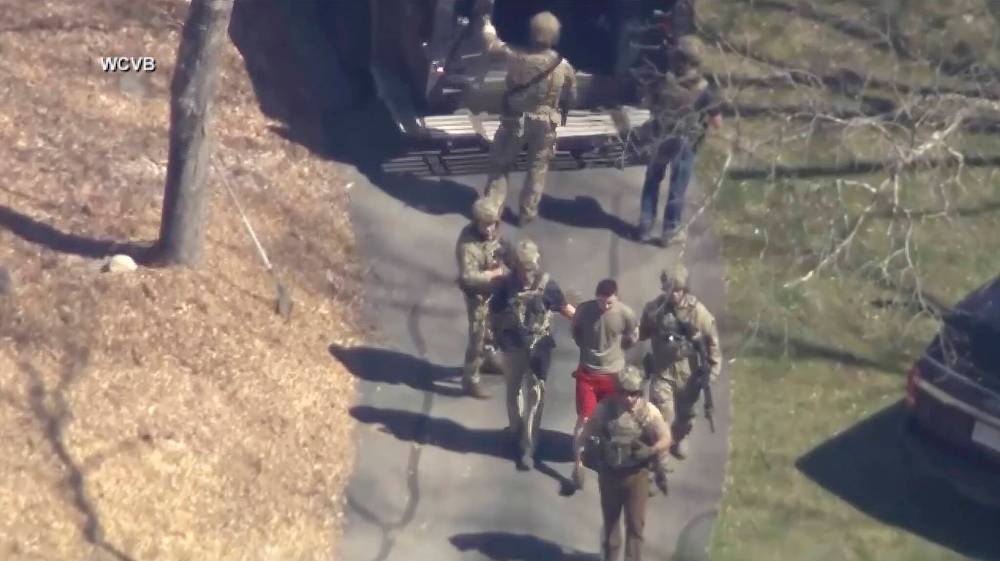 This image made from video provided by WCVB-TV shows Jack Teixeira, in T-shirt and shorts, being taken into custody by armed tactical agents in Dighton, Mass., on April 13. Teixeira, a 21-year-old IT specialist serving in the Massachusetts Air National Guard, is accused of leaking sensitive intelligence and defence information. (WCVB-TV)
