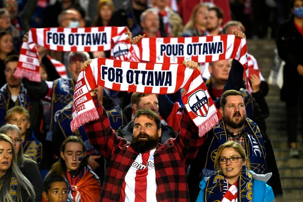 Atletico Ottawa fans raise their team's scarves before first half Canadian Premier League finals soccer action between the Atletico Ottawa and Forge FC in Ottawa on Sunday, Oct. 30, 2022. HFX Wanderers FC takes on Atletico Ottawa and York United FC faces Vancouver FC in a Canadian Championship doubleheader Wednesday at York Lions Stadium in Toronto. Atletico Ottawa is looking for its first cup win while CPL expansion side Vancouver is after its first-ever competitive victory anywhere. THE CANADIAN PRESS/Justin Tang