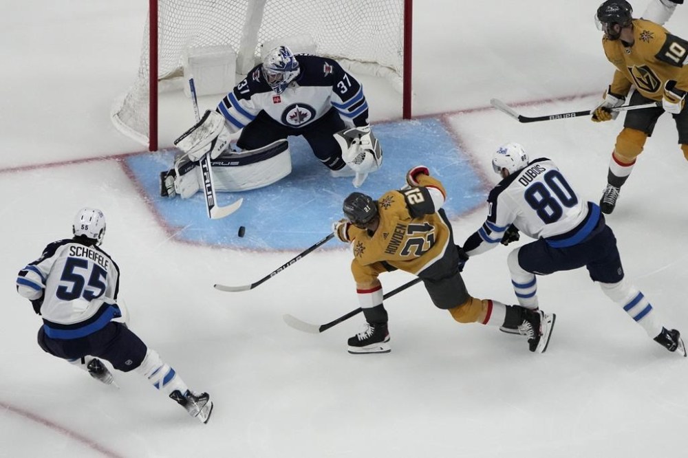 Winnipeg Jets goaltender Connor Hellebuyck (37) blocks a shot by Vegas Golden Knights center Brett Howden (21) during the first period of Game 1 of an NHL hockey Stanley Cup first-round playoff series Tuesday, April 18, 2023, in Las Vegas. THE CANADIAN PRESS/AP, John Locher