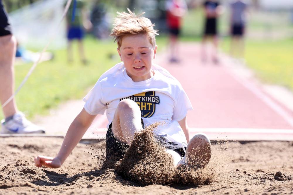 Grade 6 student Callum Wilson kicks up sand while competing in long jump during École Harrison's track and field day at the UCT Stadium on Friday. (Tim Smith/The Brandon Sun)