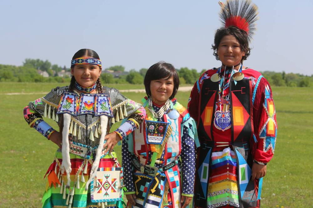 Siblings Briella, Brody and Bryce Hanska from Sioux Valley Dakota Nation, who dance together, pose for a photo before the Grand Entry.