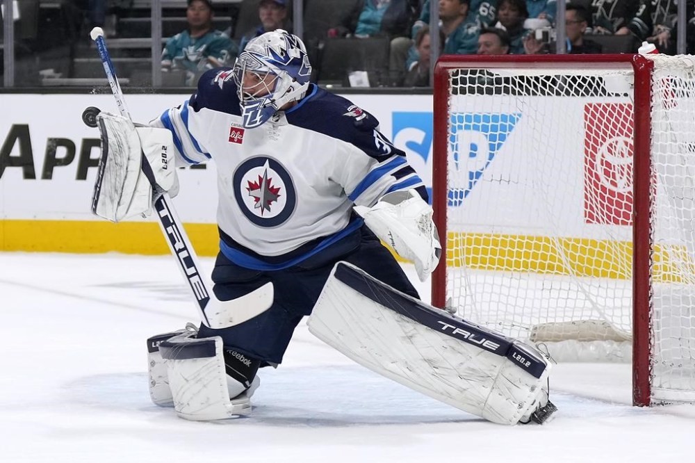 Winnipeg Jets goaltender Connor Hellebuyck blocks a San Jose Sharks shot during the first period of an NHL hockey game Tuesday, March 28, 2023, in San Jose, Calif. Winnipeg Jets goaltender Connor Hellebuyck is a finalists for the Vezina Trophy for the third time. THE CANADIAN PRESS/AP, Tony Avelar