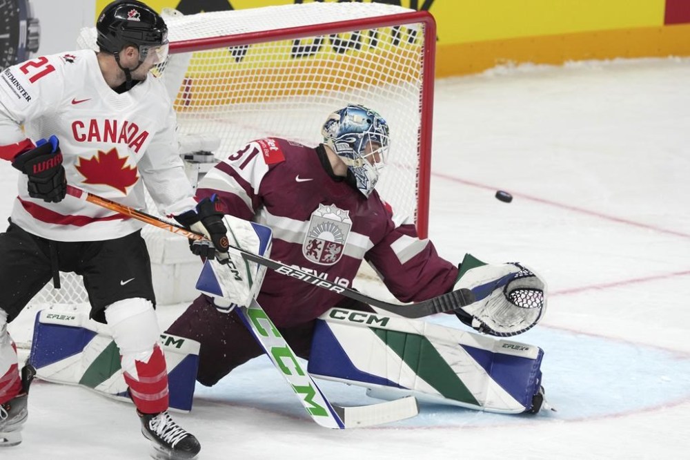 Arturs Silovs of Latvia, right, fights for a puck with Scott Laughton of Canada during the group B match between Latvia and Canada at the ice hockey world championship in Riga, Latvia, Friday, May 12, 2023. THE CANADIAN PRESS/AP-Roman Koksarov