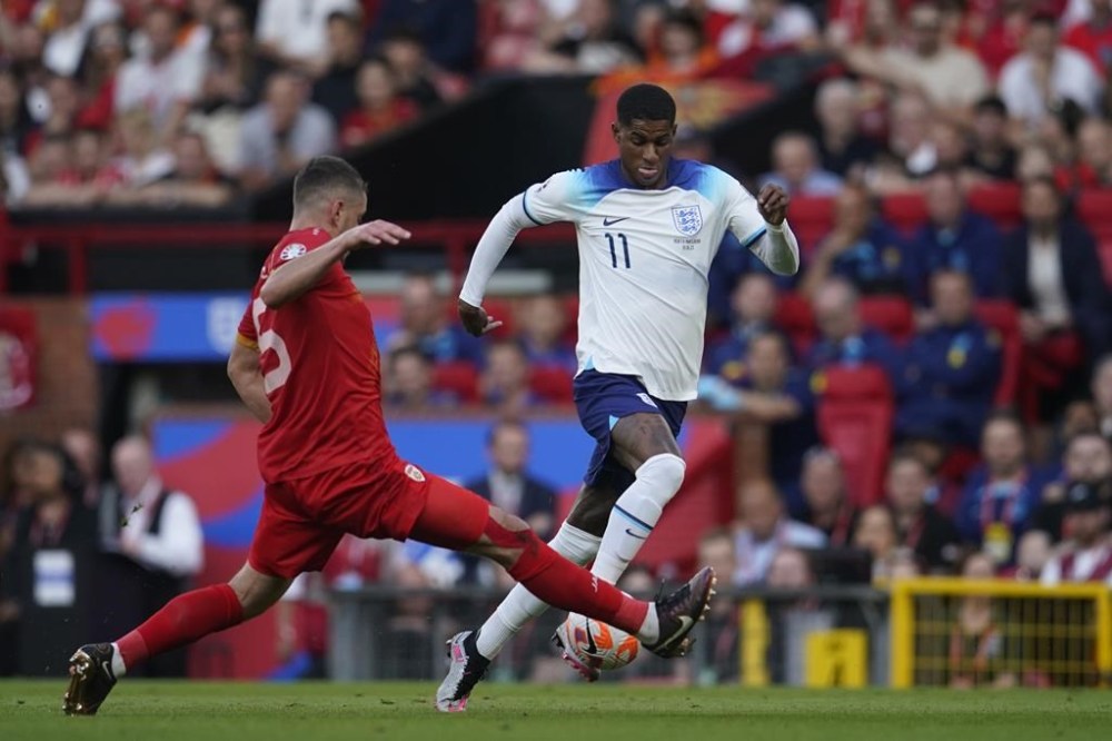 England's Marcus Rashford, right is tackled by North Macedonia's Arijan Ademi during the Euro 2024 group C qualifying soccer match between England and North Macedonia at Old Trafford in Manchester, Monday June 19, 2023. (AP Photo/Dave Thompson)
