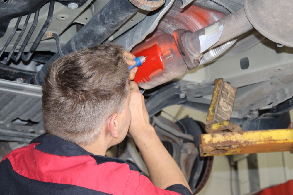 A mechanic engraves the vehicle identification number directly on to a vehicle's catalytic converter, making the part traceable if stolen. (File)