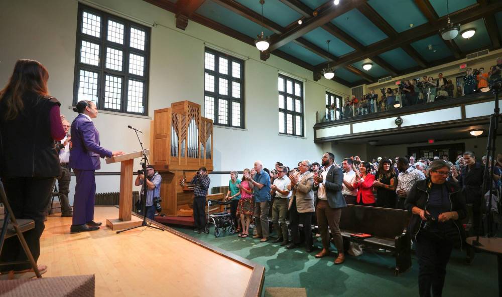Provincial NDP Leader Wab Kinew receives a standing ovation from a room full of supporters at an auditorium at Canadian Mennonite University in Winnipeg on Wednesday.