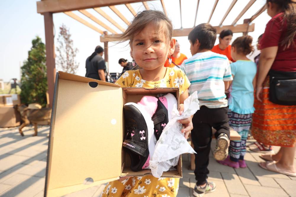 Meadow Standingready holds her pair of Under Armour shoes at the Birdtail Sioux First Nation Healing Garden on Friday. Tréchelle Bunn, founder of the Reconciliation Run, organized the donation of 213 pairs of shoes from Under Armour for children at Birdtail and helped hand out the shoes with other volunteers. Community members could also sign up for the 2023 Reconciliation Run at the event. (Photos by Tim Smith/The Brandon Sun)
