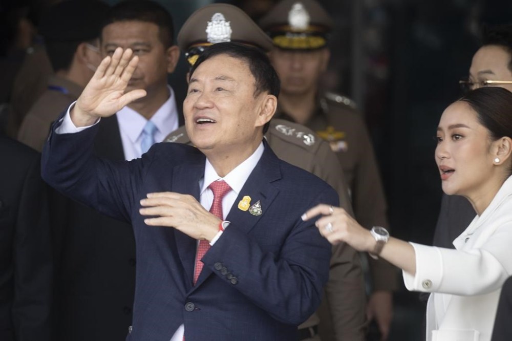 Thailand's former Prime Minister Thaksin Shinawatra, left, with his daughter Paetongtarn, right, waves to his supporters as he arrives at Don Muang airport in Bangkok, Thailand, Tuesday, Aug. 22, 2023. (AP Photo/Wason Wanichakorn)