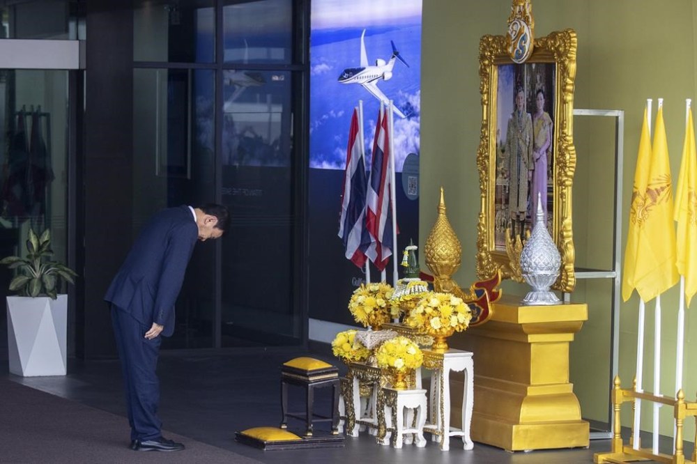 Thailand's former Prime Minister Thaksin Shinawatra prays in front of a portrait of King Maha Vajiralongkorn as he arrives at Don Muang airport in Bangkok, Thailand, Tuesday, Aug. 22, 2023. (AP Photo/Wason Wanichakorn)