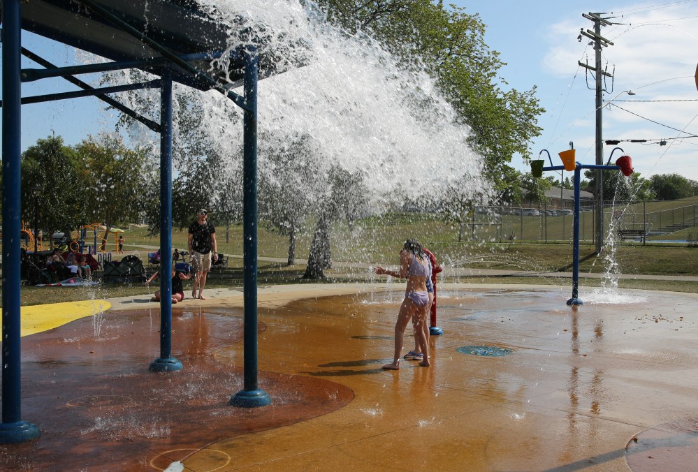Two girls brace themselves for the big bucket splash at Rideau Splash Park Wednesday afternoon in Brandon. Splash parks and pools in the city will continue operating through Sunday. (Photos by Michele McDougall/The Brandon Sun)