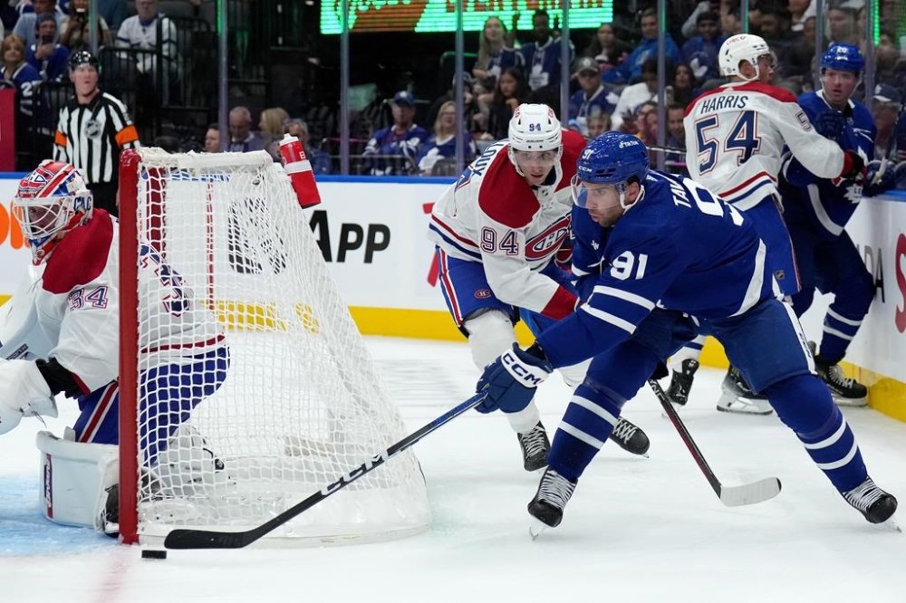 Toronto Maple Leafs centre John Tavares (91) tries for the wraparound under pressure from Montreal Canadiens' Logan Mailloux (94) during second period NHL preseason hockey action in Toronto, Monday, Oct. 2, 2023. THE CANADIAN PRESS/Nathan Denette