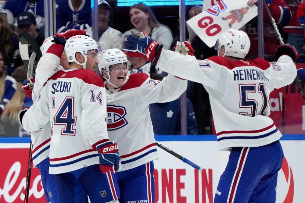 Montreal Canadiens right wing Cole Caufield (22) celebrates his team's game-winning goal with teammates Nick Suzuki (14) and Jordan Harris (54) during overtime NHL preseason hockey action against the Toronto Maple Leafs, in Toronto, Monday, Oct. 2, 2023. THE CANADIAN PRESS/Nathan Denette
