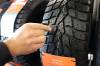 Brayden Davis points out the wear bar that is built into the Sumitomo winter tire in the company's shop in Brandon.