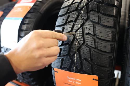 Brayden Davis points out the wear bar that is built into the Sumitomo winter tire in the company's shop in Brandon.