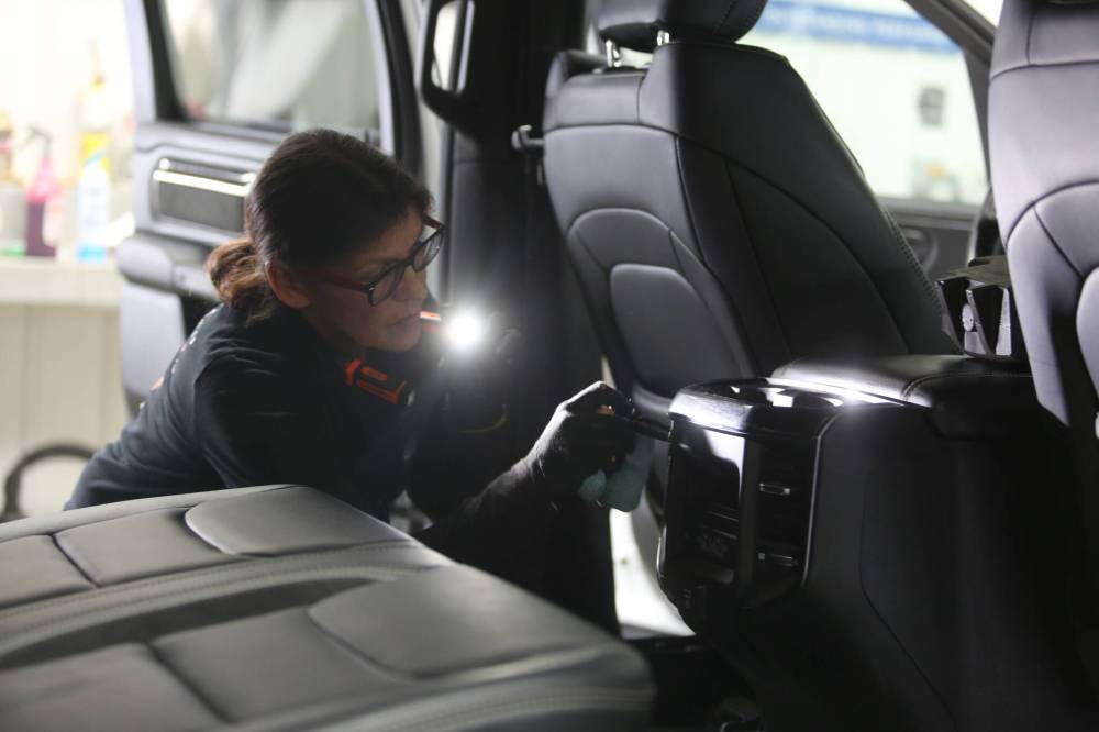 Shawn Simpson, a detailer with Resurrection Auto Detailing Tint and Protection, uses a flashlight while cleaning a truck's interior at the company's shop on Thursday.