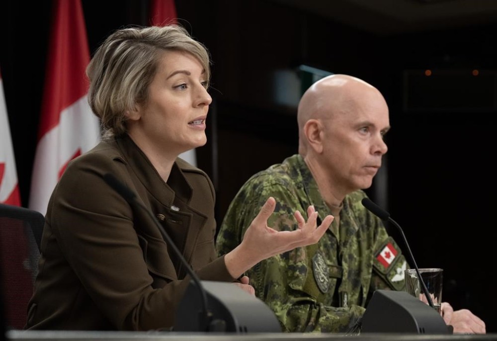 Foreign Affairs Minister Melanie Joly says the first group of Canadians living in the West Bank have safely crossed into neighbouring Jordan as violence continues in Israel's escalating war against Hamas. Chief of the Defence Staff Wayne Eyre listens as Joly responds to a reporter's question during a news conference in Ottawa, Wednesday, Oct. 11, 2023. THE CANADIAN PRESS/Adrian Wyld