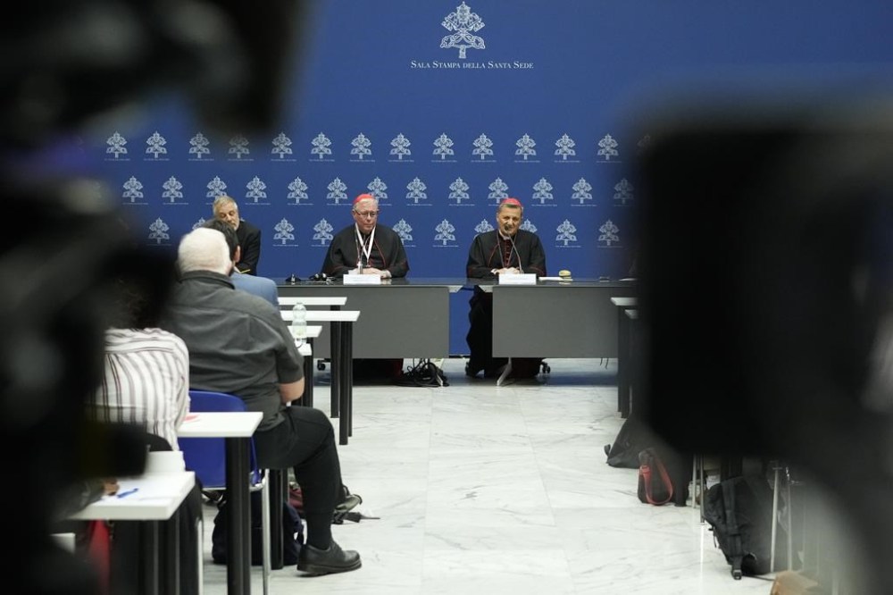 Cardinals Mario Grech, right, and Jean-Claude Hollerich tap to reporters during a press conference for the closing of the 16th general assembly of the synod of bishops, at the Vatican's press room in Rome, Saturday, Oct. 28, 2023. (AP Photo/Andrew Medichini)