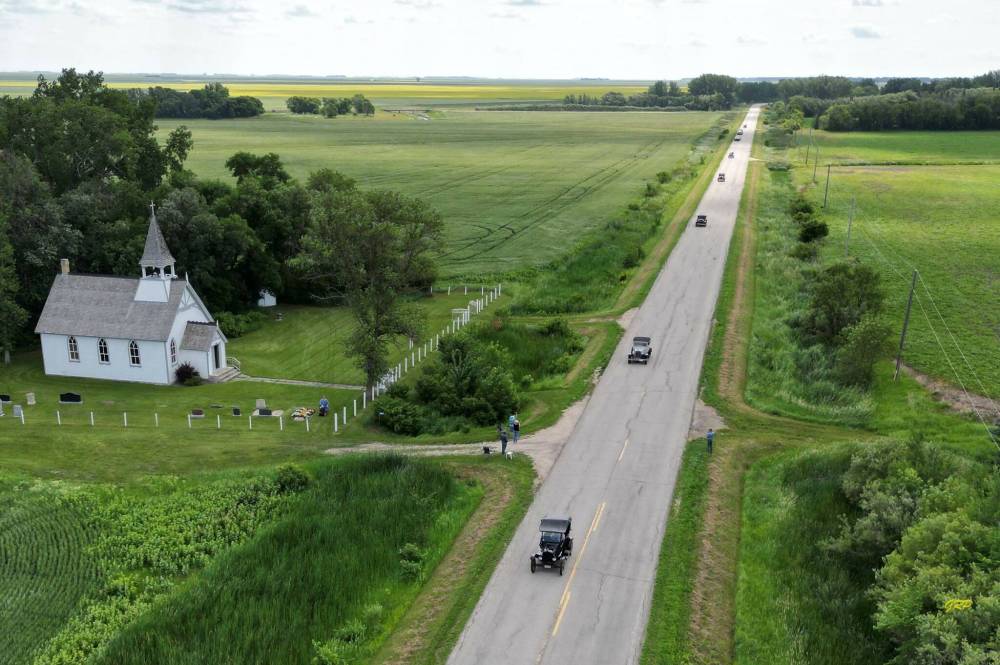 Five antique cars during last summer's Pine to Prairie Relic Run on the original Trans-Canada Highway, now Provincial Trunk Highway in the RM of Saint Francois Xavier with St. Paul’s Anglican Church on the left. (Photos by George Penner)
