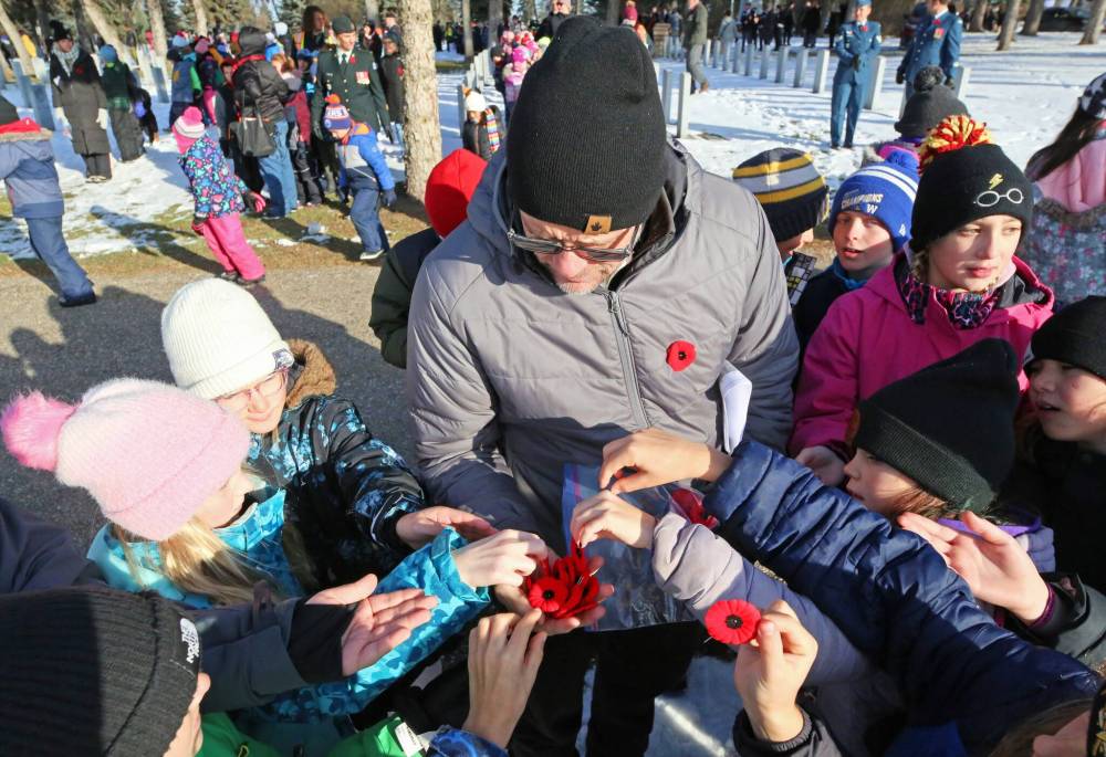 Greg Sylvestre, a Grade 5 teacher at École Harrison, hands out poppies to his students that will be placed at the graves of Canadian Forces members following the No Stone Left Alone ceremony at the Brandon Municipal Cemetery on Friday morning. (Photos by Matt Goerzen/The Brandon Sun)