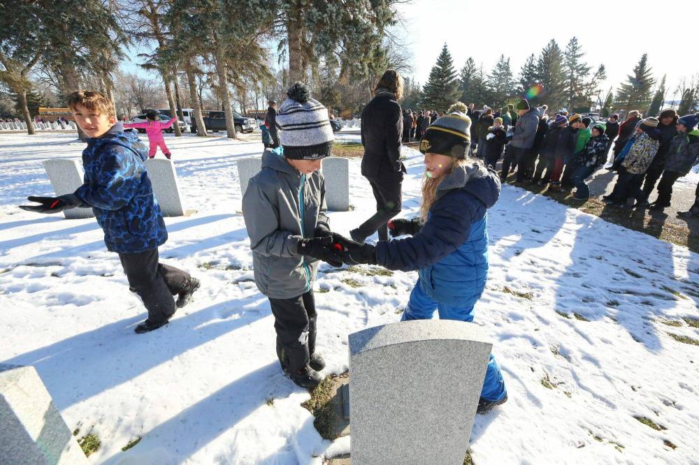 Grade 5 École Harrison student Nash Taylor, right, hands a poppy to fellow Grade 5 student Van Druwe.